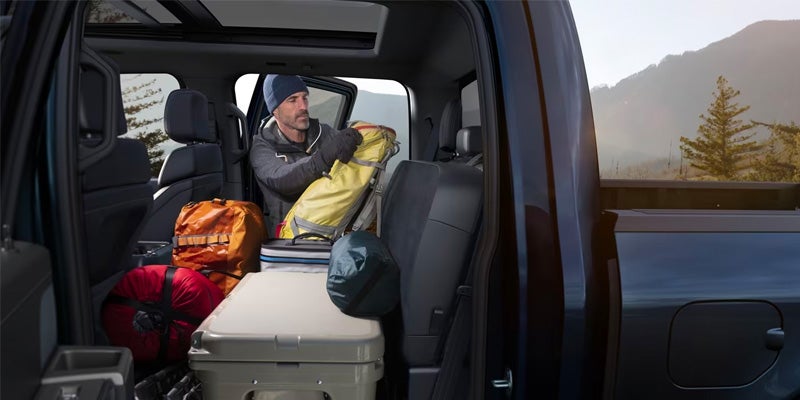 Man unloading camping gear from F-150 backseat